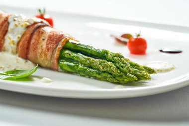 Pastırmalı ızgara kuşkonmaz ve beyaz tabakta hardal sosu. Arkaplanda izole edilmiş.