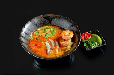 Karides, şitake mantarı, ahtapot, domates ve pirinçli Asya Tom çorbası. Klasik Asya mutfağı. Yemek servisi. Siyah üzerine izole edilmiş.