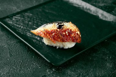 Zencefil ve wasabi ile siyah tahtada yılan balıklı Nigiri suşisi. Japon mutfağı. Yemek servisi. Siyah arkaplan