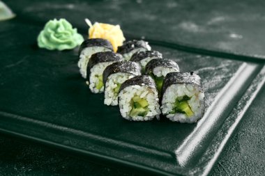 Salatalıklı Maki suşi rulosu. Klasik Japon mutfağı. Yemek servisi. Siyah arkaplan