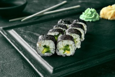 Salatalıklı Maki suşi rulosu. Klasik Japon mutfağı. Yemek servisi. Siyah arkaplan