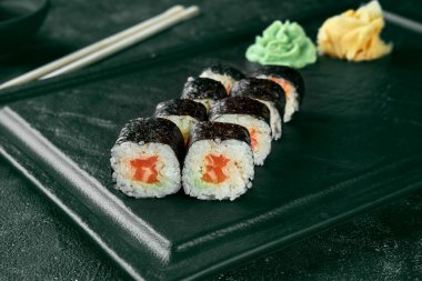 Maki suşisi ve somon. Klasik Japon mutfağı. Yemek servisi. Siyah arkaplan