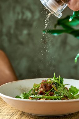 Dana etli karabuğday çorbası, kişniş sosu ve beyaz tabakta pak choi. El biberi tabağa.