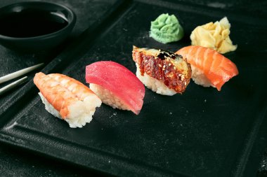 Somon, yılan balığı, ton balığı ve karidesli Nigiri suşisi. Japon mutfağı. Yemek servisi. Siyah arkaplan