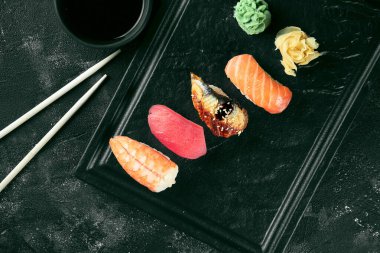 Somon, yılan balığı, ton balığı ve karidesli Nigiri suşisi. Japon mutfağı. Yemek servisi. Siyah arkaplan
