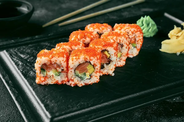 Uramaki sushi california roll in tobiko caviar with salmon, avocado and cucumber. Classic Japanese cuisine. Food delivery.