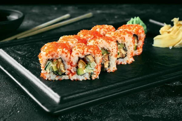 Uramaki sushi california roll in tobiko caviar with eel, avocado and cucumber. Classic Japanese cuisine. Food delivery. Isolated on white.