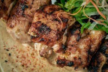 Beyaz barbekü soslu ızgara biftek, salatalık ve ahşap arka planda bir tabakta sos.