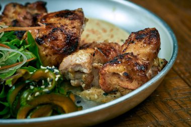 Beyaz barbekü soslu ızgara biftek, salatalık ve ahşap arka planda bir tabakta sos.