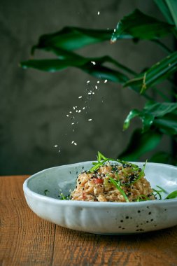 Sebzeli pirinç tavuğu ve ahşap bir arka planda bir tabakta tavuk. Asya mutfağı. Susam tohumları tabağa dökülür.
