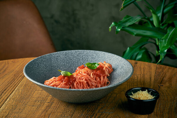 spaghetti pasta with tomato sauce and basil in a gray plate. italian cuisine