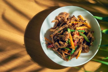 Biberli baharatlı Sichuan tavası eti, susam tohumu, havuç ve yeşil domates. Çin mutfağı.