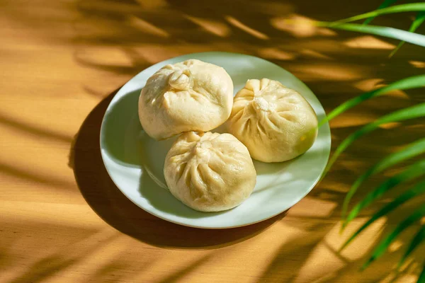 Baozi with different fillings (beef or pork) in a white plate. Chinese recipe and cuisine. Chinese steamed meat bun