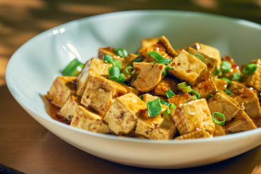 Sichuan biberi ve beyaz tabakta sebze ile tatlı ve ekşi soslu kızarmış tofu. Çin mutfağı.