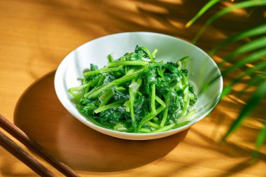 İstiridye soslu Çin ıspanak salatası ve beyaz tabakta sarımsak.