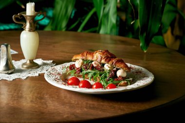 Mozarella, roka, ahşap arka planda kurutulmuş domatesli kruvasan sandviçi.