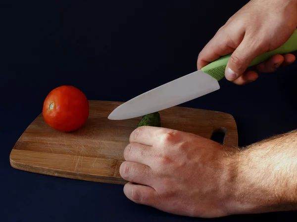 Les mains de l'homme coupent le concombre vert Image En Vente