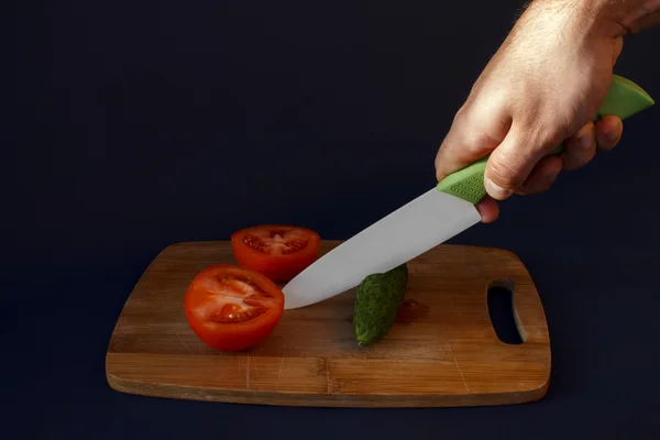 Les mains de l'homme coupent le concombre vert Photo De Stock