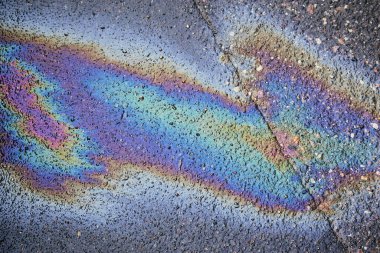 Gas stain on wet asphalt caused by a leak under a car or truck, abstract background clipart