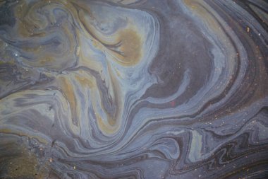 Soyut gökkuşağı etkisi, ıslak asfaltta renkli gaz lekesi. Yaya kaldırımındaki bir arabadan sonra gökkuşağı benzin sızıntısı..