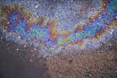 Asfaltta yağ lekesi, asfalt yolda renkli benzin lekeleri doku veya arka plan olarak su birikintisine akıyor.