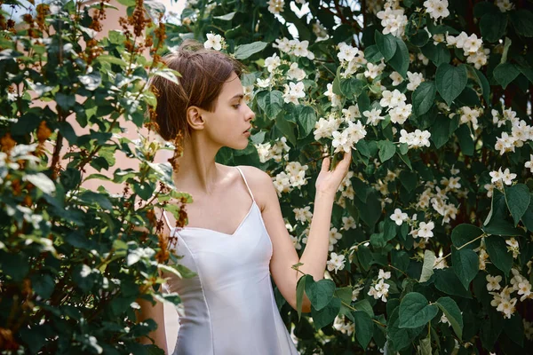 Attractive modest young girl natural makeup in a white dress outdoors, tenderness and softness against the background of nature