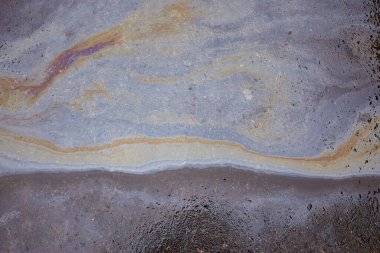 Asfalt yolundaki benzin lekesinin dokusu ya da arkaplanı olarak. Islak asfaltta renkli gaz lekesi.