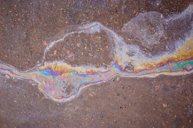 Benzin asfalt yüzeyinde akıyor. Yanardöner benzin lekeleri..