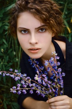 Elinde bir buket lupinle genç bir kadın.