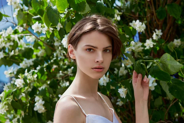Attractive modest young woman natural makeup in a white dress outdoors, tenderness and softness against the background of nature