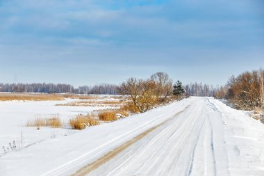 Güneşli bir günde göl boyunca karlı bir yol.