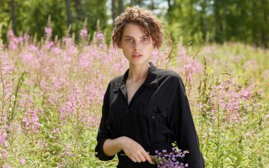 Güneşli bir yaz gününde çiçek açan İvan Çayı 'nın arka planında genç bir kadın. Gençlik kavramı.