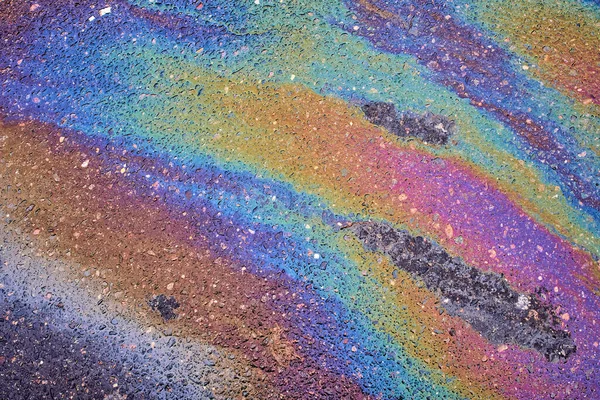 Gas stain on wet asphalt caused by a leak under a car or truck, abstract background