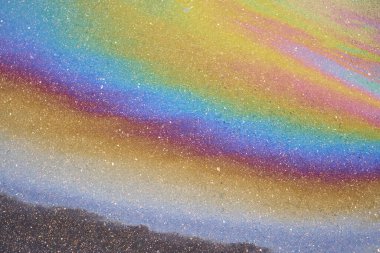 Islak asfalttaki yağ lekesi bir arabanın ya da kamyonun altındaki sızıntıdan kaynaklanıyor. Çevresel petrol kirliliği.