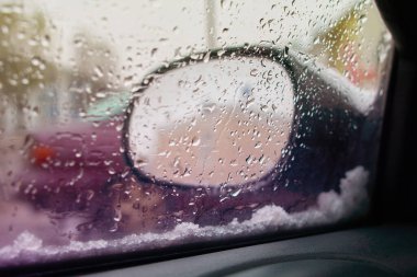 Akşam vakti, şehir caddesinde yağmur yağarken arabanın içinden görüntüyü aç. Yumuşak seçici odak