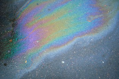 Soyut gökkuşağı etkisi arka plan, ıslak asfalt üzerindeki renkli gaz lekesi bir arabanın veya kamyonun altındaki sızıntıdan kaynaklanıyor. Çevre kirliliği kavramı.