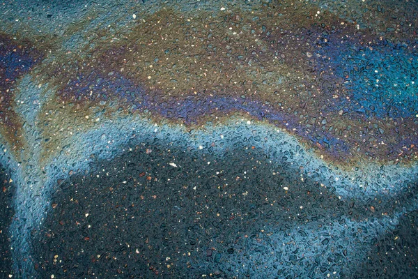 Abstract rainbow effect background, colorful gas stain on wet asphalt caused by a leak under a car or truck.Environmental pollution concept.