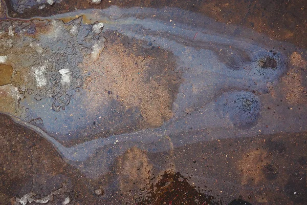 iridescent spot of gasoline on pavement as Texture or Background