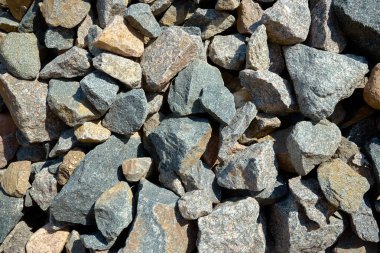 Büyük taş parçalarının gri dokusu bir taş ocağında parçalanmış ve düzensiz şekil ve boyutlara bölünmüş..