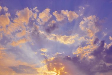 Gün batımında güneş ışınları tüylü bulutların farklı renklerini aydınlatır