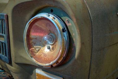 Kırık farlı, paslı, yeşil bir arabanın ön tarafında.