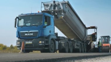 Novosibirsk Bölgesi, 15 Ağustos 2020 Yol işçileri asfalt karışımını bir kamyonun arkasından kaldırımlara yüklüyorlar..