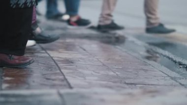 Bir grup yaya yağmurdan sonra ıslak asfalt üzerinde yolu geçmeye başlar. Kalabalık bir yaya geçidi trafiği vardı. Şehir hayatı. İsimsiz kalabalık. Yavaş çekim.
