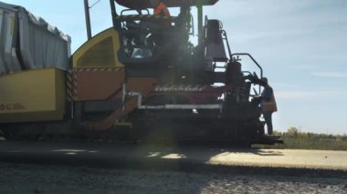 Novosibirsk bölgesi, 15 Ağustos 2020. Asfalt kaldırımının kontrol panelinde bir yol işçisi. Yeni bir yol inşaatı. Yol yüzeyi onarımı.