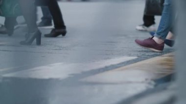 Novosibirsk, 15 Ağustos 2020. Bir grup yaya yağmurdan sonra ıslak asfalt üzerinde yolu geçti. Kalabalık bir yaya geçidi trafiği vardı. Koşan insanların bacaklarına yakın çekim. Yavaş çekim.