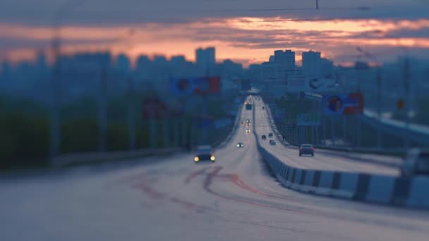 Linsenunschärfe. Autos fahren vor dem Hintergrund der Stadtsilhouette über die Brücke. Panoramablick auf einen wunderschönen Sonnenaufgang in einer europäischen Stadt. Kipp- und Shift-Linse — Stockvideo