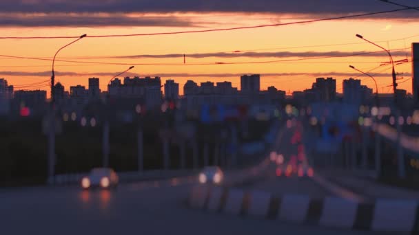 Obiektyw zamazany. Samochody jeżdżą na tle sylwetki. Panoramiczny widok na piękny zachód słońca w europejskim mieście. Soczewka obrotowa — Wideo stockowe