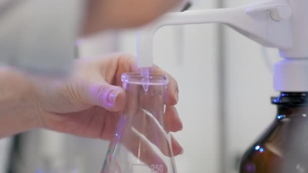 Yakın plan. Laboratuvar kimyacısı tarifleri hacimli bir şişede karıştırıyor. COVID-19 Aşı Araştırma Laboratuvarı. — Stok video