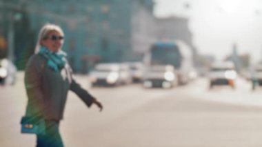 Lensler bulanık, bulanık. Bir yaya kalabalığı geçen arabaların arka planına karşı caddeyi geçiyor. İnsanlar güneşli bir günde yürürler. Şehir hayatı. Yavaş çekim