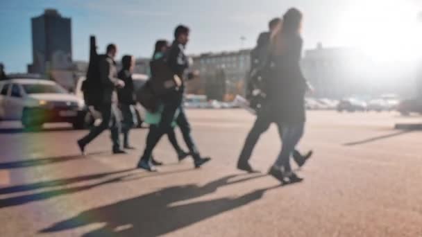 Desenfoque de la lente, fuera de foco. Una multitud de peatones está caminando por la calle con coches en el fondo. La gente camina por la gran ciudad en un día soleado. Movimiento lento — Vídeos de Stock